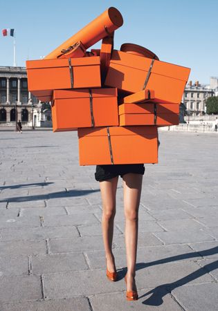 vrouw met stapel oranje Hermes dozen